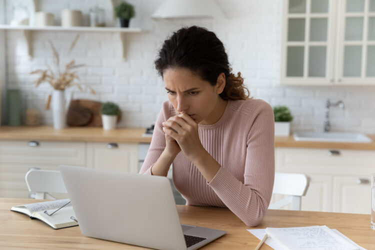 Hard to decide. Anxious worried woman freelancer sit at kitchen workplace meet difficult problem mistake ponder on decision. Scared young lady think by laptop screen troubled with debt blackmail