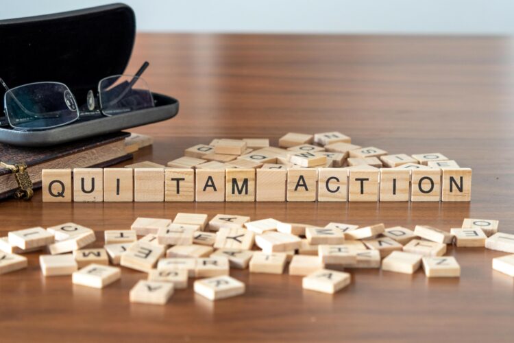 qui tam action word or concept represented by wooden letter tiles on a wooden table with glasses and a book